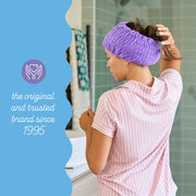 A woman facing away, wearing a purple turbie band with her hair tucked in. On the left side of the picture, there is text that reads, ''The original and trusted brand since 1995''